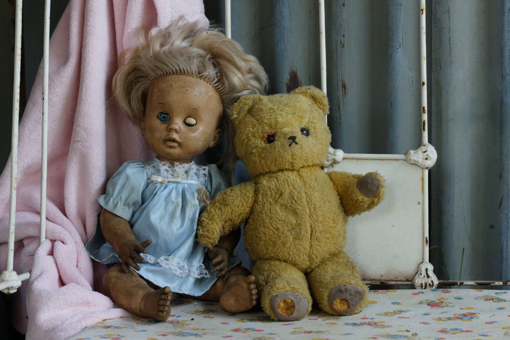 A creepy doll and aged teddy bear